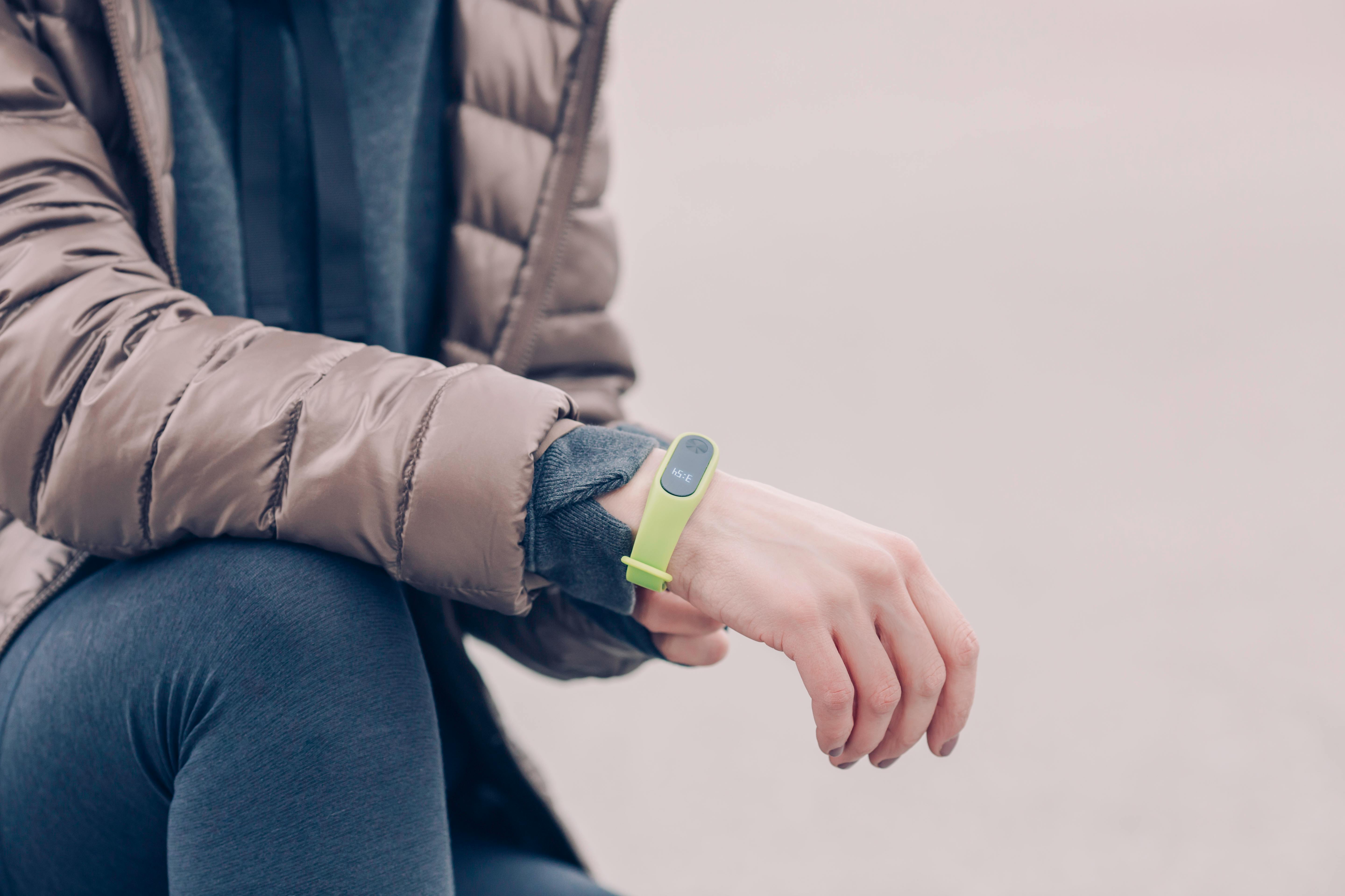 Person wearing a fitness tracker band on wrist outdoors