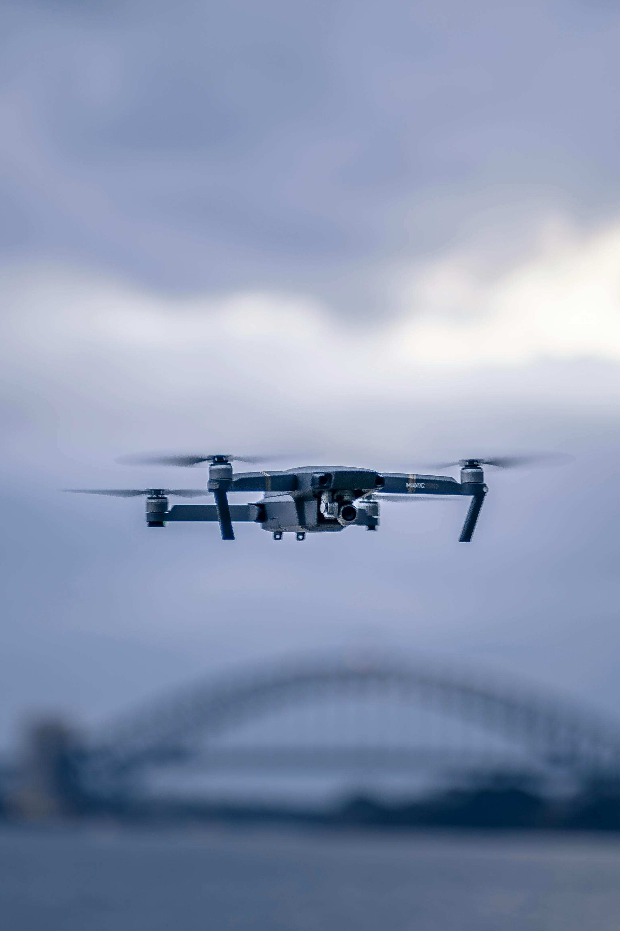 Drone flying in front of Sydney Harbour Bridge against cloudy sky