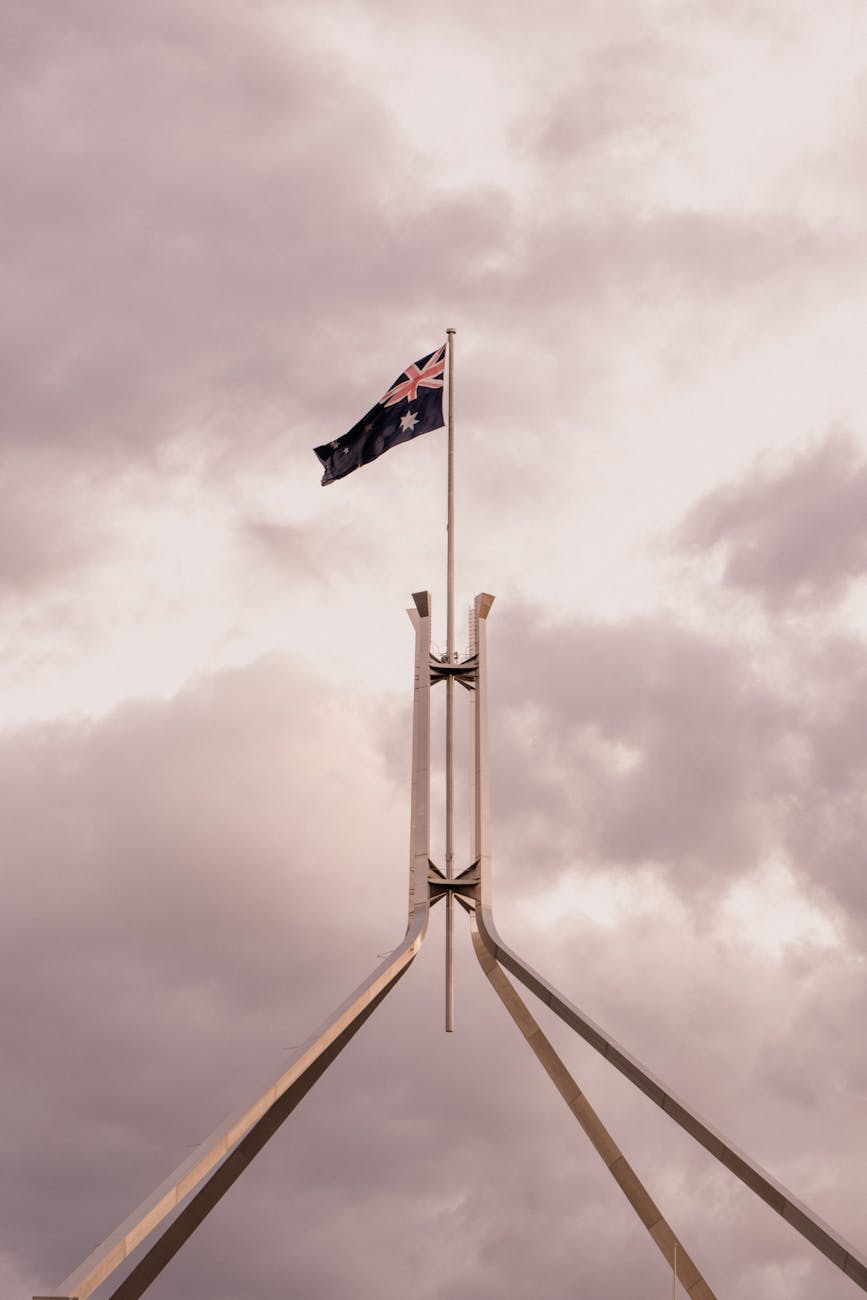 Australian flag flying over Parliament House, Canberra, against a cloudy sky