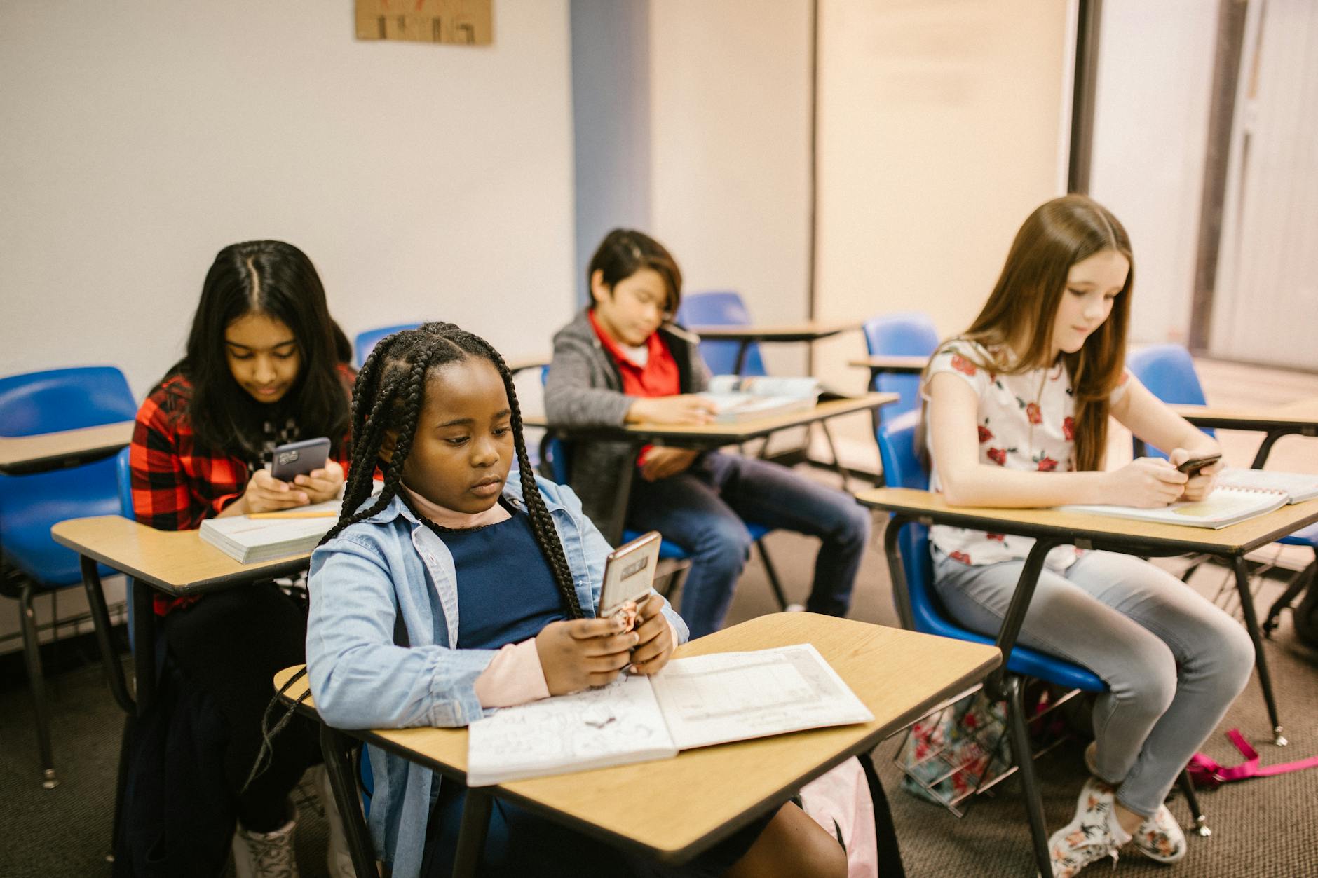 Students using smartphones and notebooks during a classroom lesson