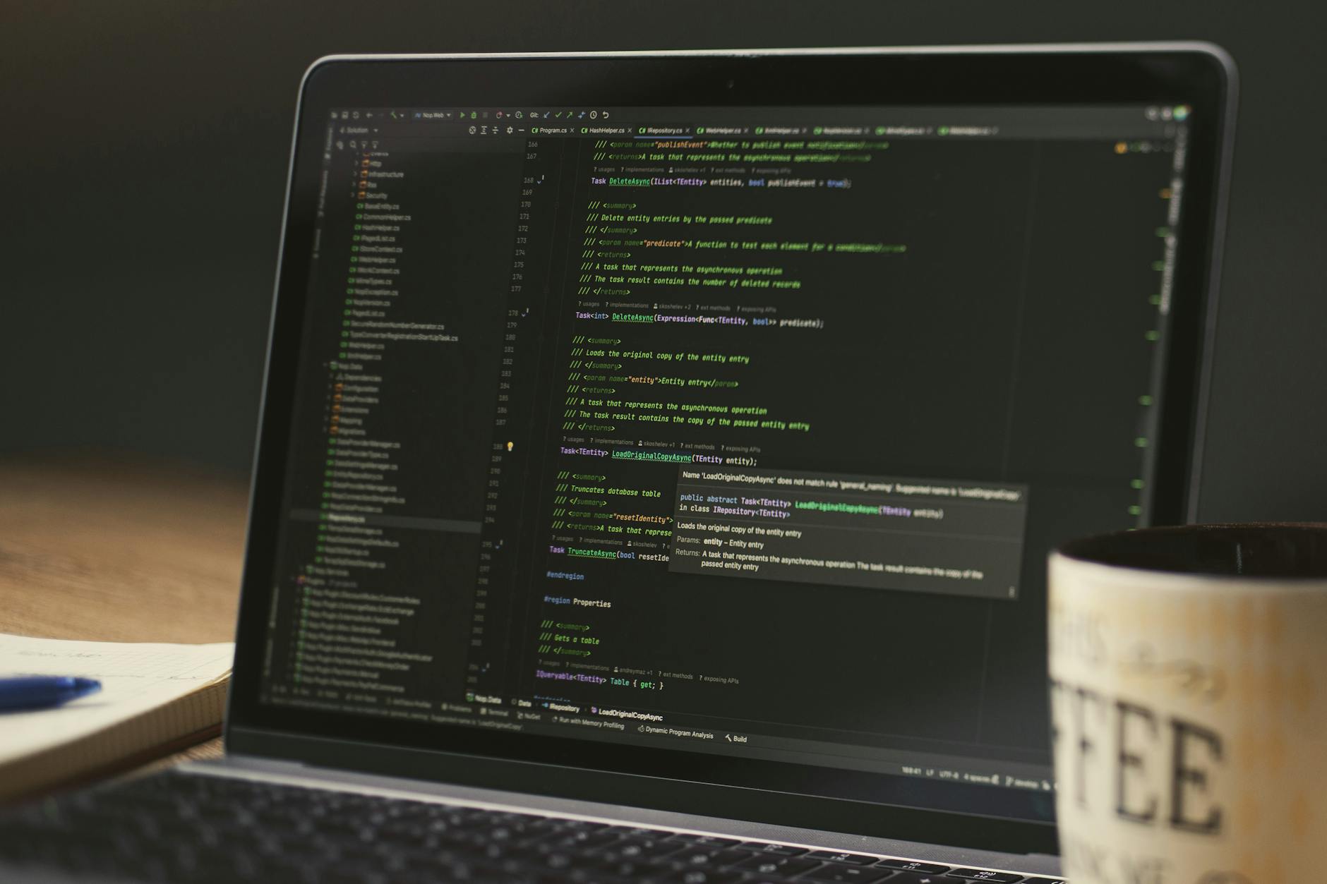Software developer at a laptop with code editor visible in dim lighting