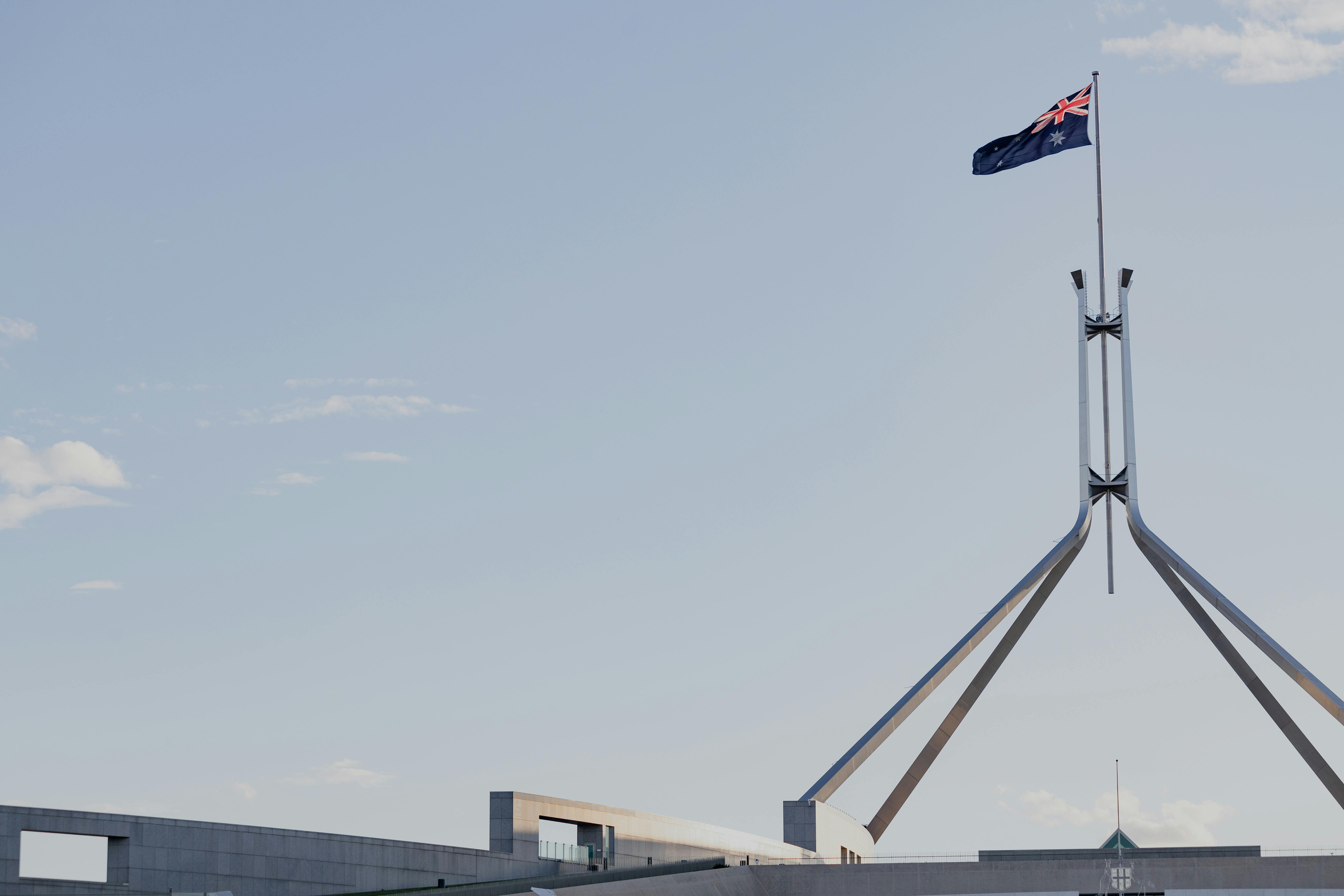 Australian Parliament House in Canberra with the national flag against a clear blue sky