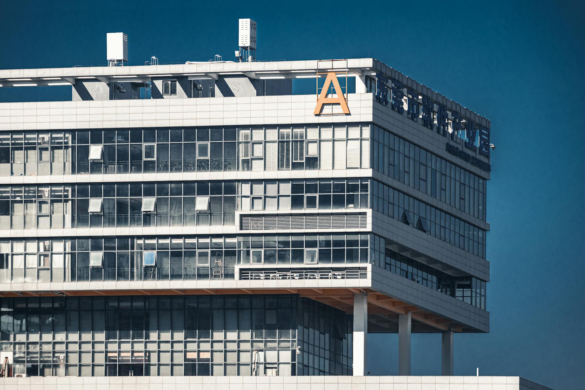 Modern glass-facade office building under clear blue sky