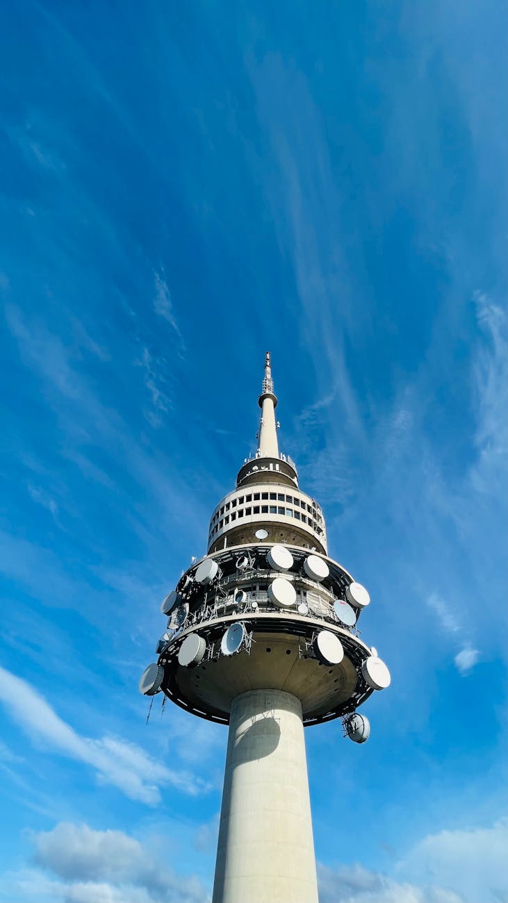 Low-angle view of Telstra Tower in Canberra, Australia with clear blue sky.