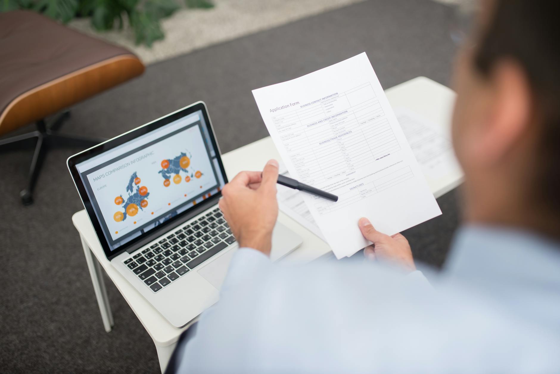 Consultant reviewing security research documents on a laptop in an office