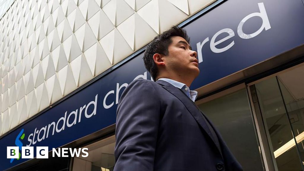 A pedestrian walks past a Standard Chartered bank branch in Hong Kong.