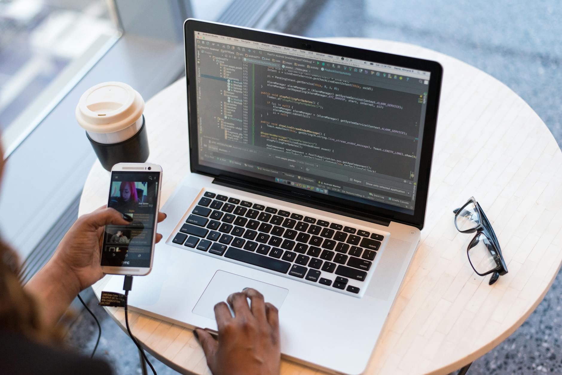 A developer working on code beside an Android smartphone, illustrating the prompt-to-prototype workflow Google is pushing into AI Studio.