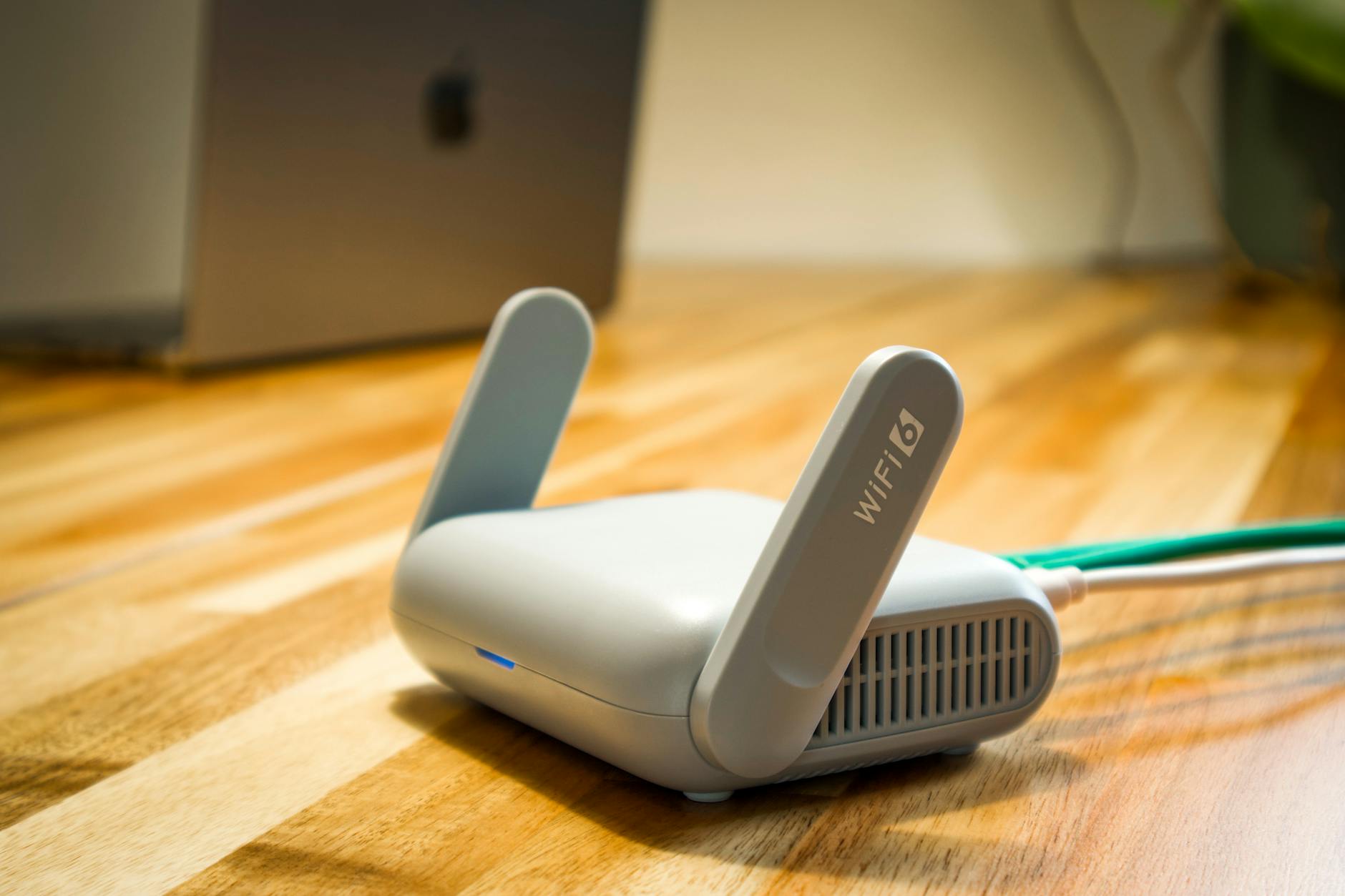 Wi-Fi 6 router on a desk beside connected broadband cabling