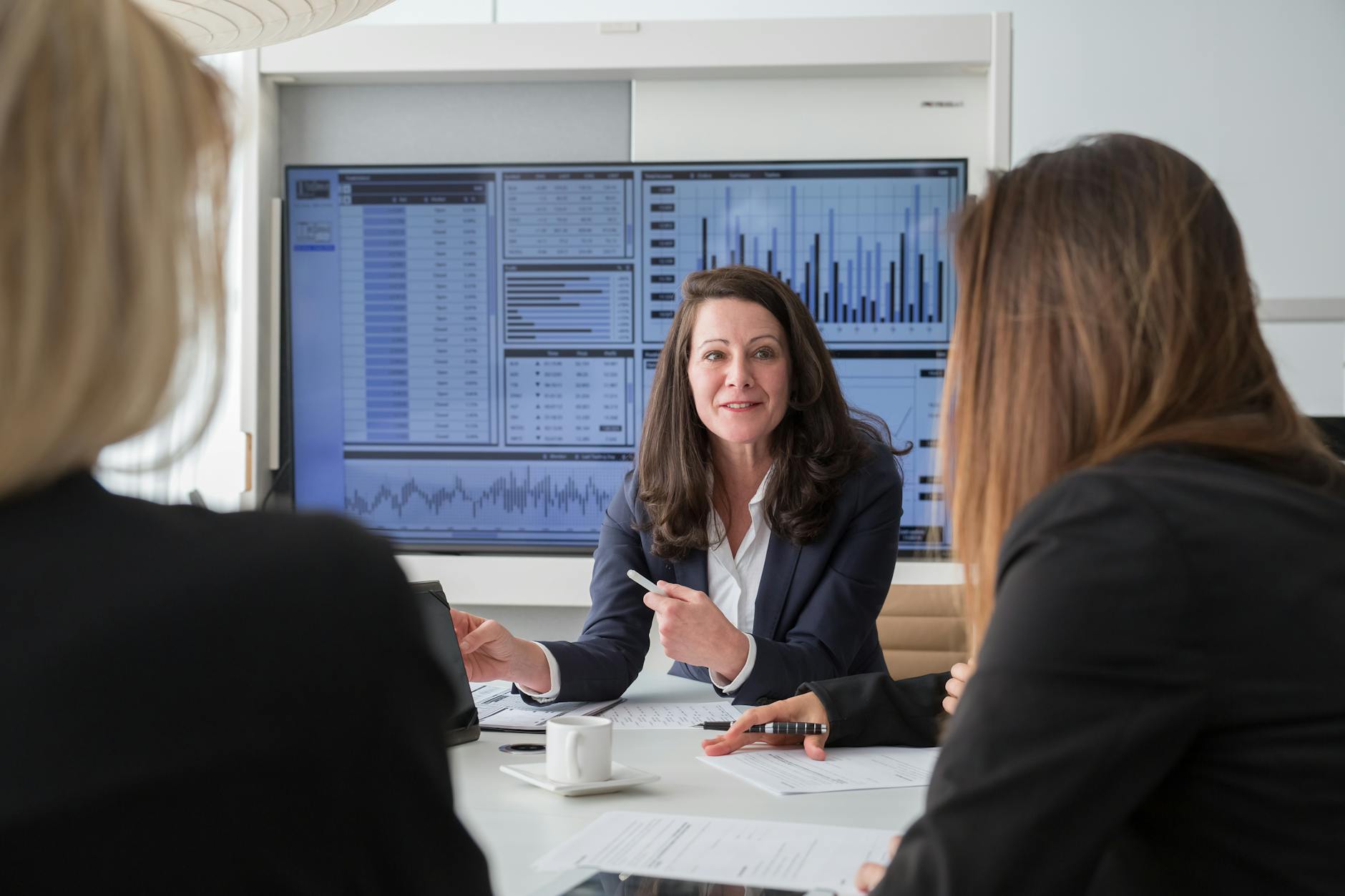 Business executives in a boardroom discussing strategy in front of a data presentation screen.