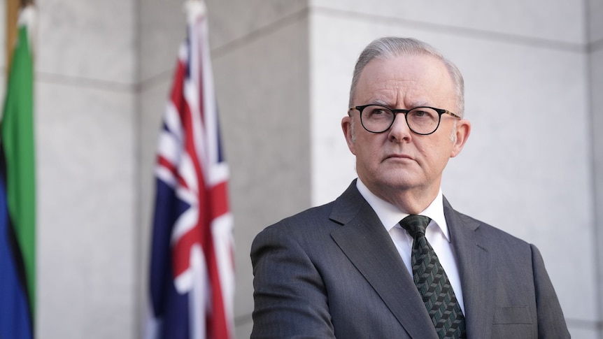 Prime Minister Anthony Albanese with the Australian flag behind him.