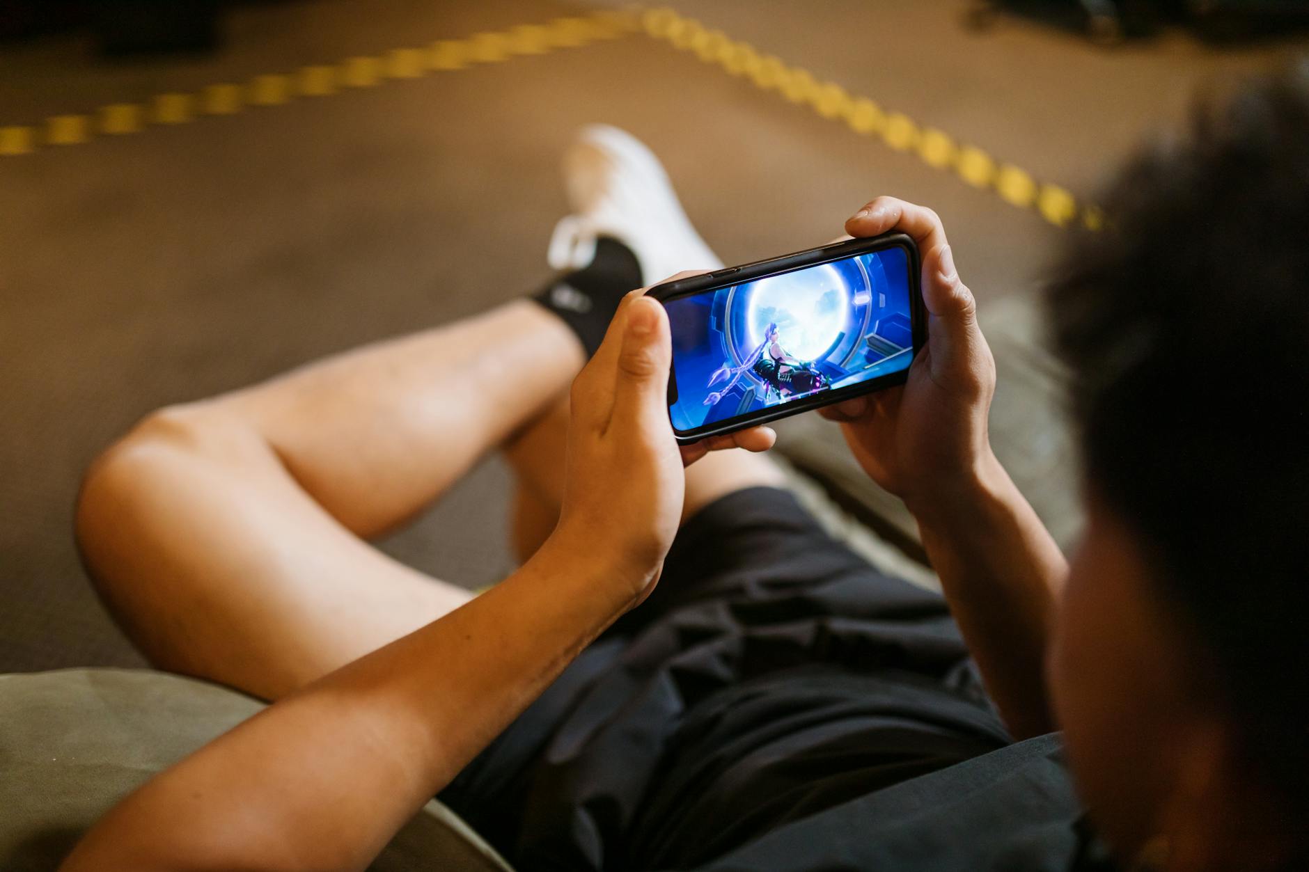 Mobile gamer using a smartphone with RGB lighting, illustrating gaming-phone buying choices in Australia