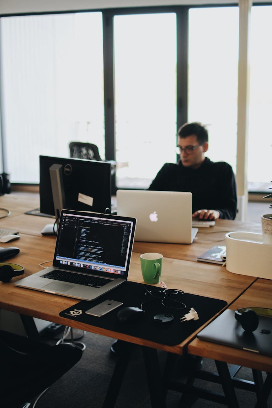Web developer working across laptop and desktop screens in a modern office