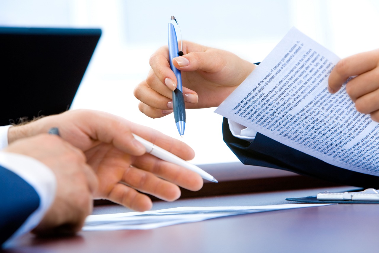 Laptop beside handwritten notes and printed pages during a document review
