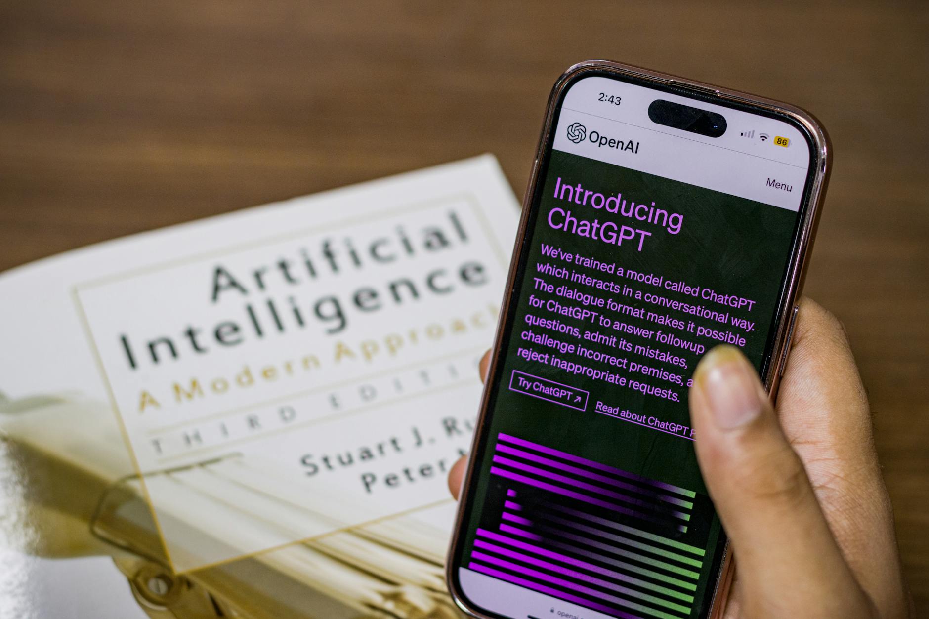 A smartphone displaying ChatGPT over an artificial intelligence textbook