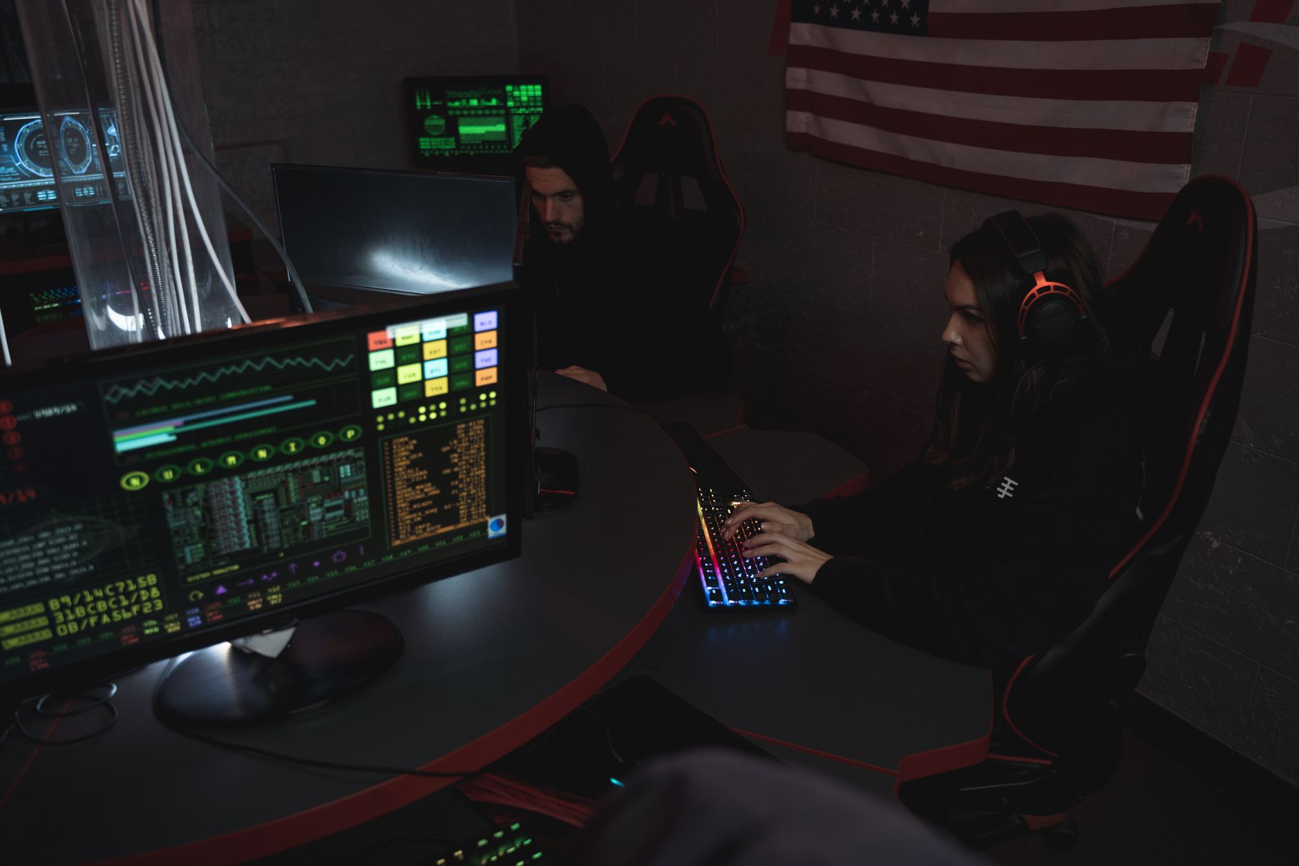 Cybersecurity professionals working on computer systems in a dimly lit operations room