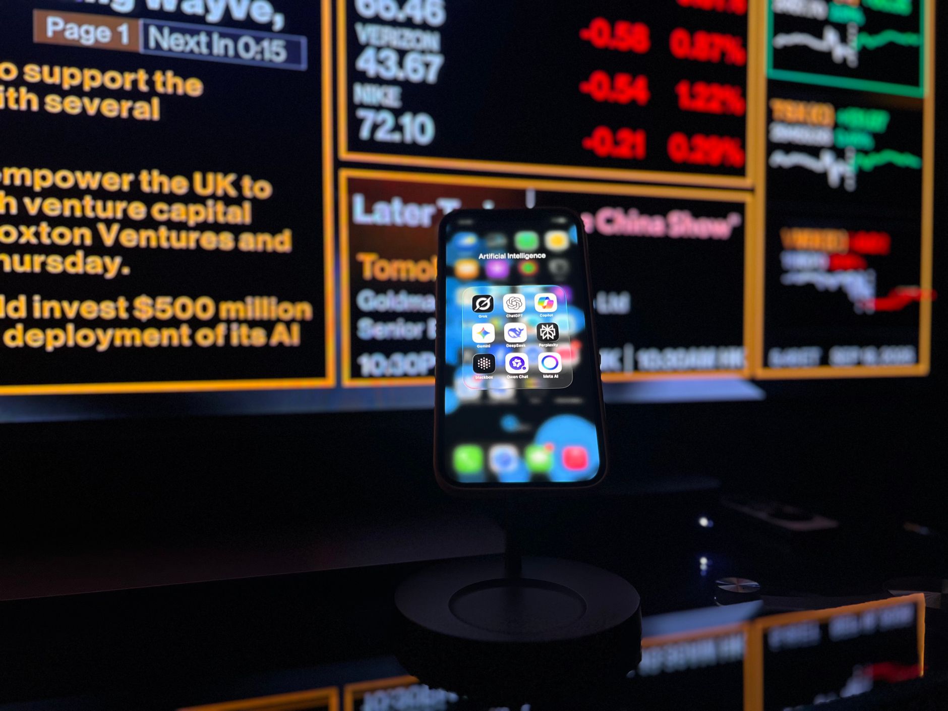 Smartphone showing AI apps in front of a market data screen